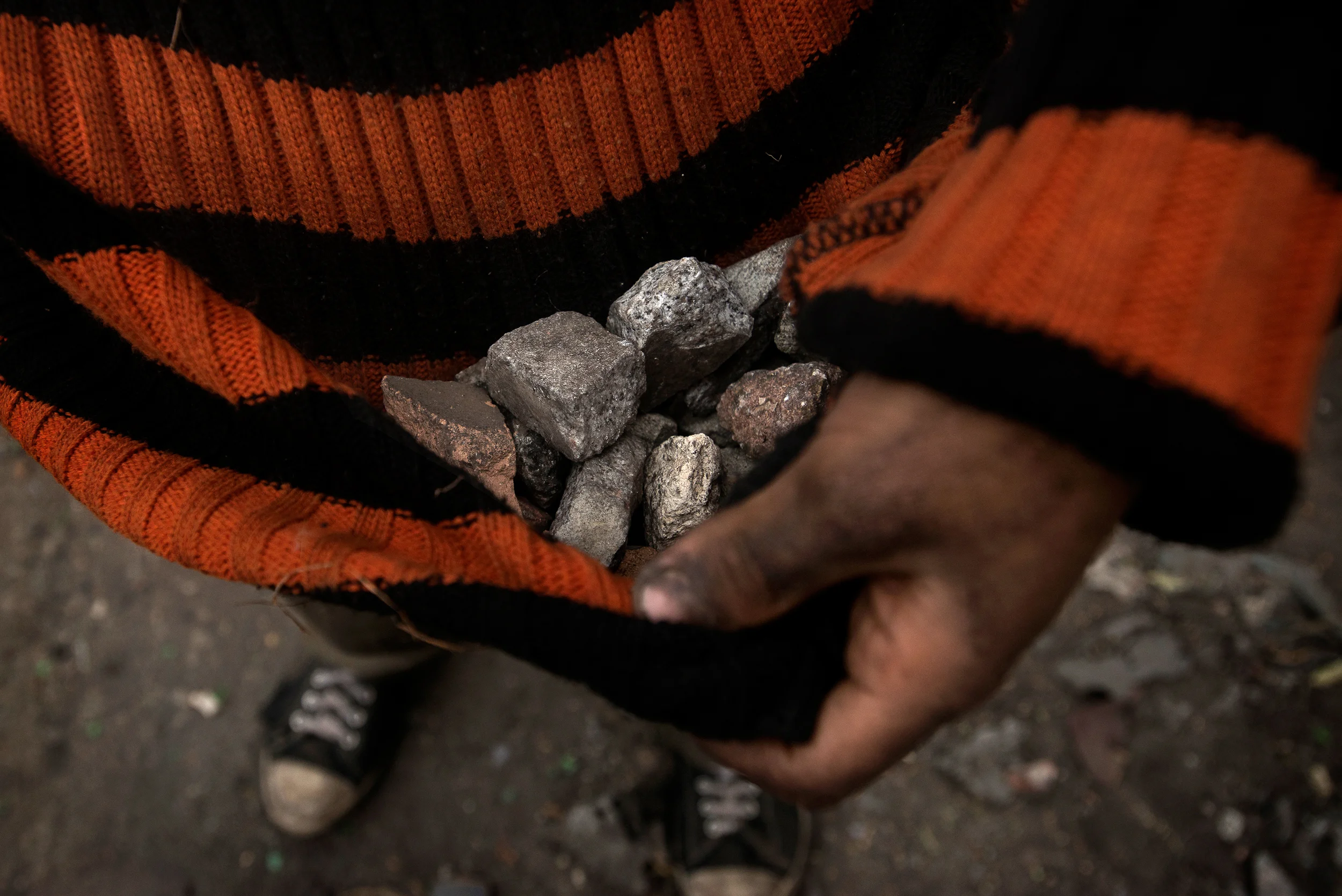 A young boy keeps a pile of stones in his sweater as he joins protesters as they clash with police in Tahrir Square in Cairo on the eve of the second anniversary of the uprising that overthrew Hosni Mubarak. The protesters tried to dismantle a wall of concrete blocks that blocked a street leading to the square.