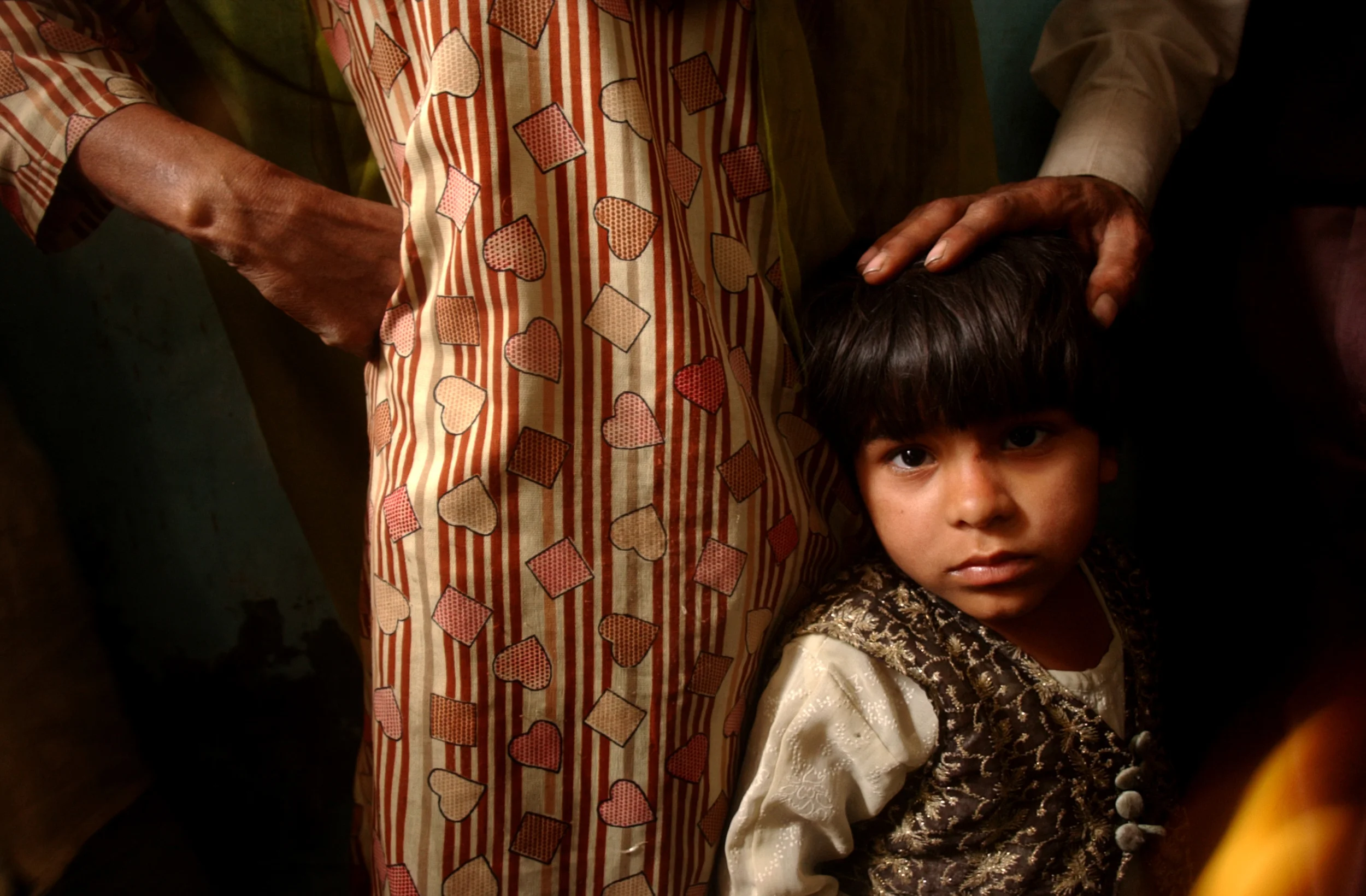 A father places his hand on his son's head as he is convinced to allow his child to be immunized for polio in Muzzafarnager, India in February 2005.