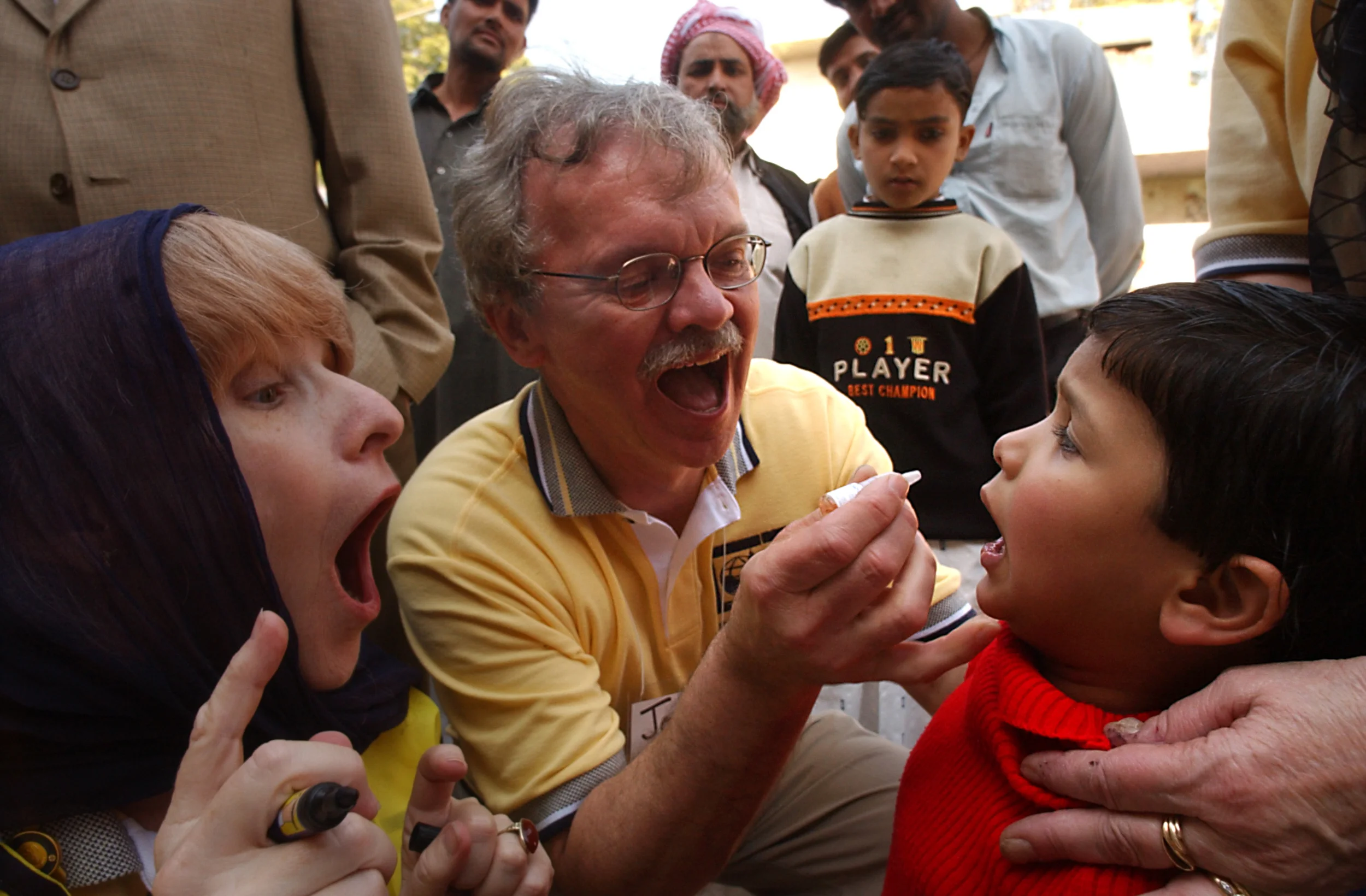 Rotarians Andrea Shields, 57, of Rancho Cucamunga, Calif., a clinical psychologist and Joseph Tafelski, 58, Toledo, Ohio a legal aid attorney help administer the oral polio vaccine to a child in Muzzafarnagar, a district in the polio endemic state of Uttar Pradesh, India during the countries National Immunization Days in February 2004.