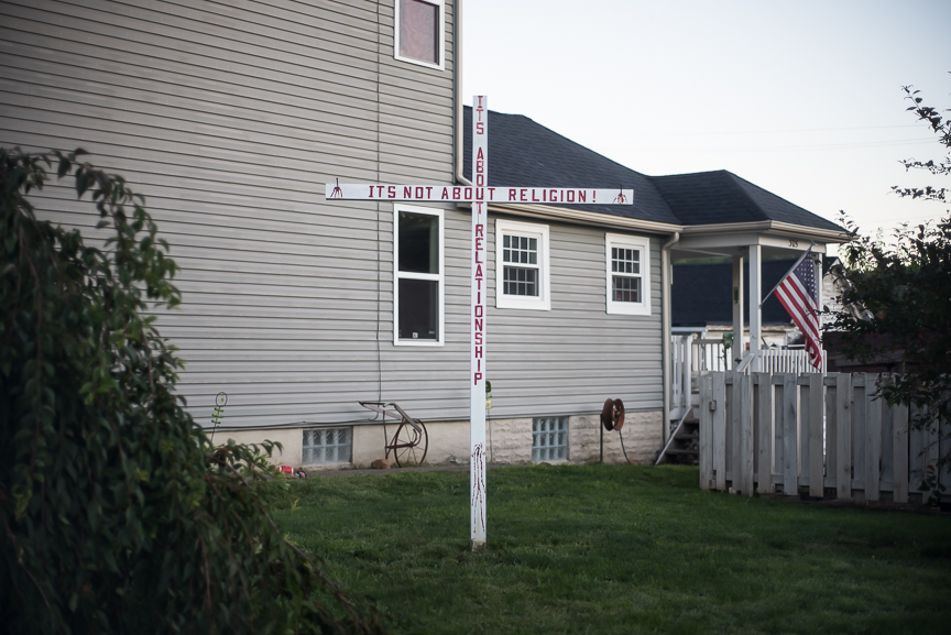 A cross painted with "It's not about religion! It's about relationships" stands in a yard along West 6th Street in East Liverpool, Ohio on Sept. 15, 2016.
