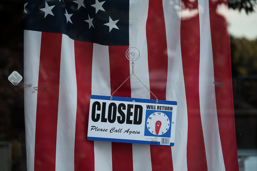 A closed sign hangs in front of a flag in a storefront in East Liverpool, Ohio on Thursday, Sept. 15, 2016.