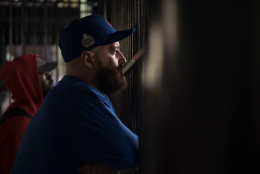 Stephen Caton, 29, of St. Louis, a Chicago Cub fan watches game 6 of the World Series through a fence at Progressive Field on November 1, 2016 in Cleveland, Ohio. 