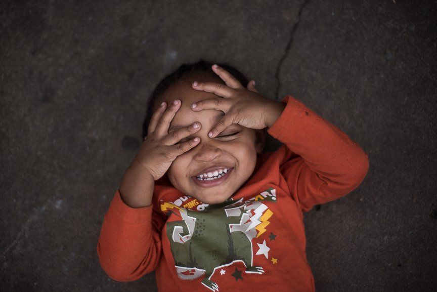 Dorian Baker, 2, lays on the ground and laughs at a family gathering to celebrate his 2nd birthday at his Braddock home on April 3, 2017.