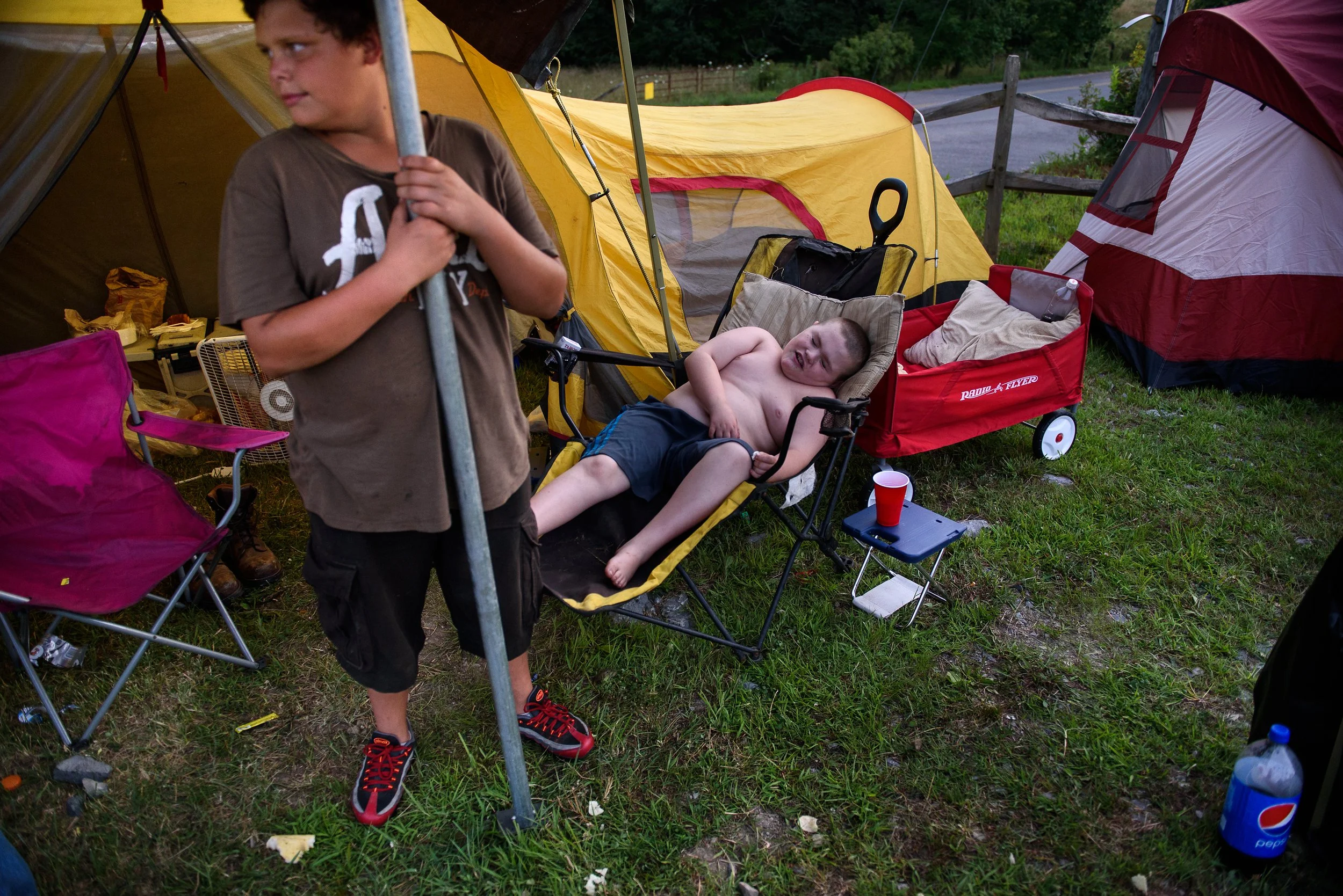  Issac Vanderpool, 9, of Kingsport, Tenn., right, lays down in a chair near his family's tent and his cousin, Dominic Stewart, 11, left, as they prepare to spend the night in the parking lot of the Wise County Fairgrounds on Thursday evening, July 20