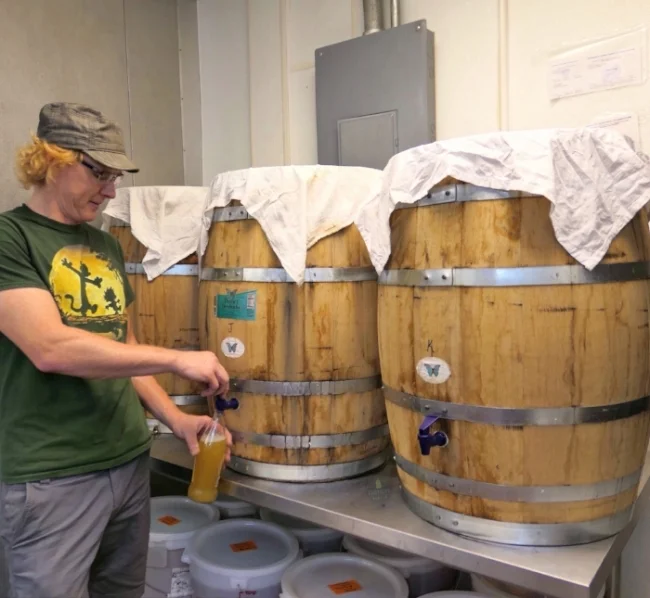 Deane Kombucha founder Bryan Bertsch pours off a sample from his oak barrel fermenters.