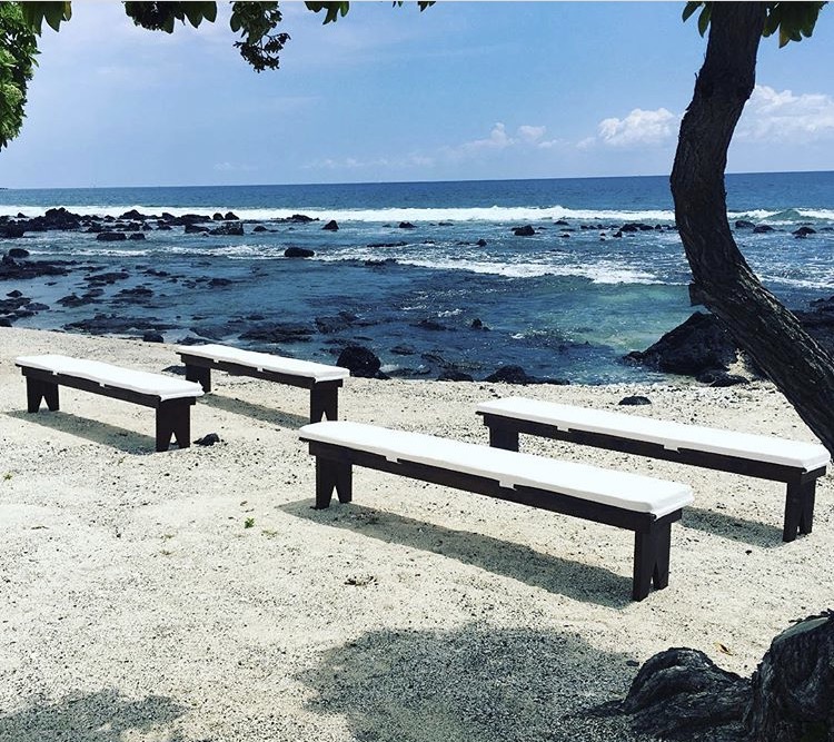 Dark Wood Benches with white cushions, set up on the beach for an intimate wedding.
