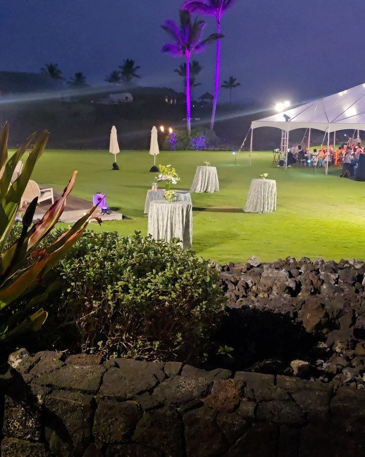 Contrast - Wedding at kukio north featuring our 40x clear tent with chandeliers, cross back vineyard chairs, LED dance floor, white leather lounge furniture, silver rimmed plateware, glassware, rose gold chargers, umbrellas, catering trays and stands