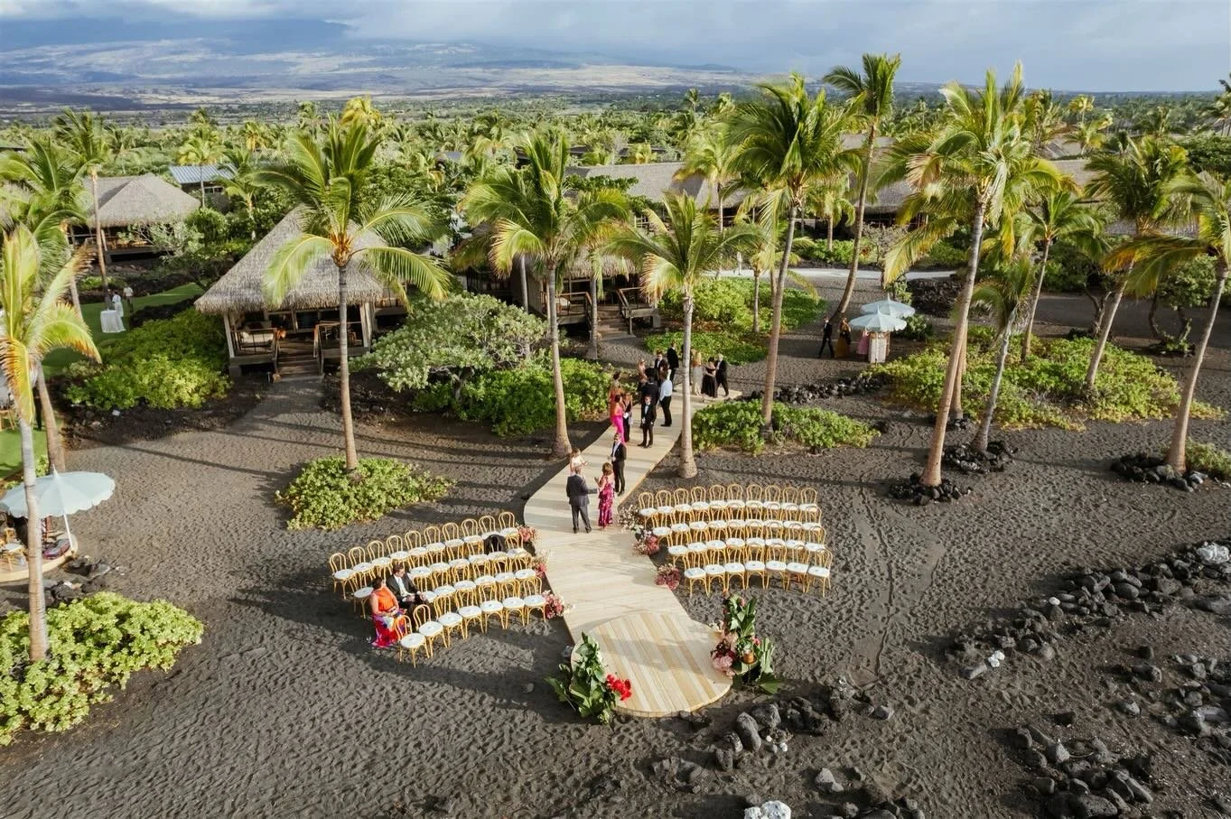 An architectural aisle way of natural wood, softened by the ocean breeze and grounded by black sand. 

Custom built natural wood plank walkway and ceremony platform 
Natural bentwood chairs. 

Planning &amp; Design @maeandco_creative
Venue @konavilla