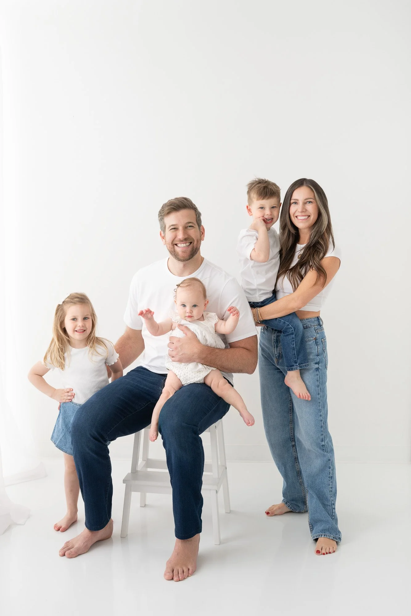 NJ family in white t-shirt and jeans in bright white photography studio