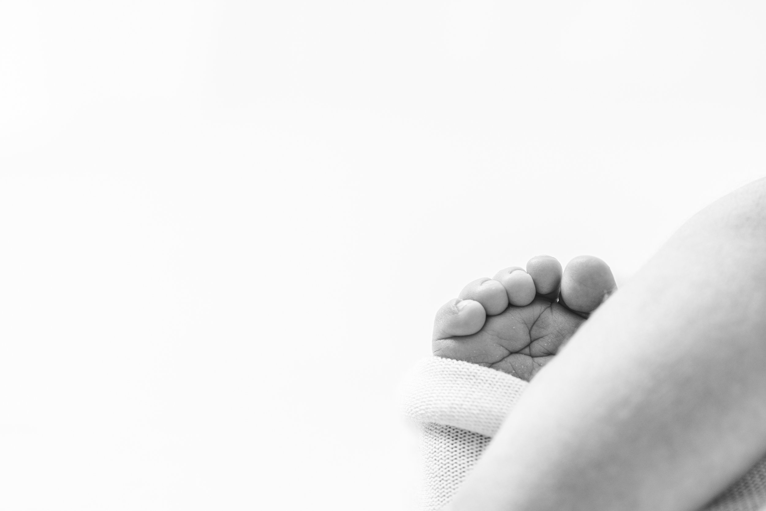  A black and white detailed close-up photo of a baby's foot and little toes by Nicole Hawkins Photography, a professional New Jersey photographer. high end newborn photographers NJ professional newborn photographers #nicolehawkinsphotography #nicoleh