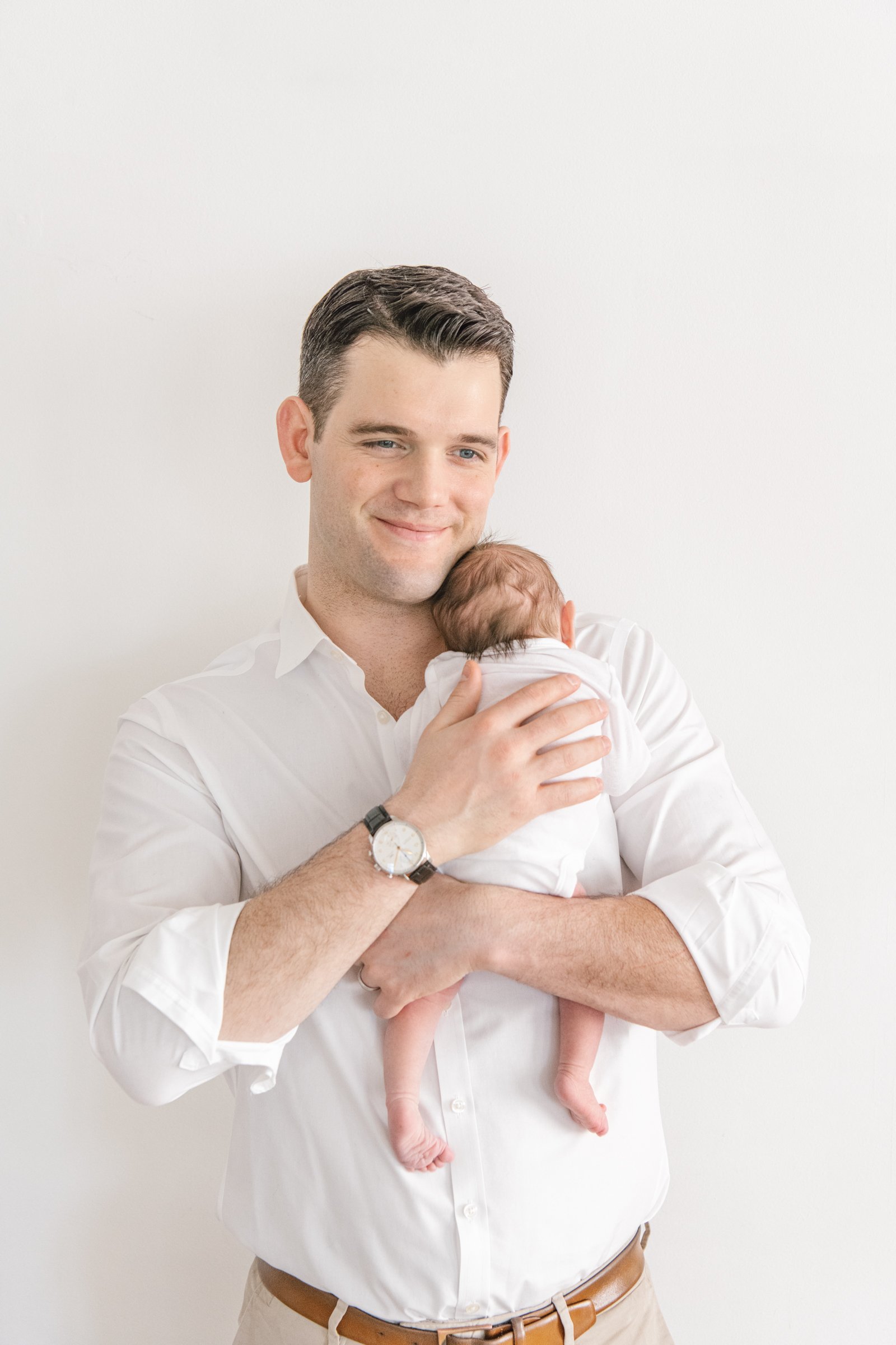  Father holding a sweet baby girl and patting her back capturing a new father moment by Nicole Hawkins Photography a New Jersey photography. father and baby white onesie on baby brown belt for father New Jersey newborn session #nicolehawkinsphotograp