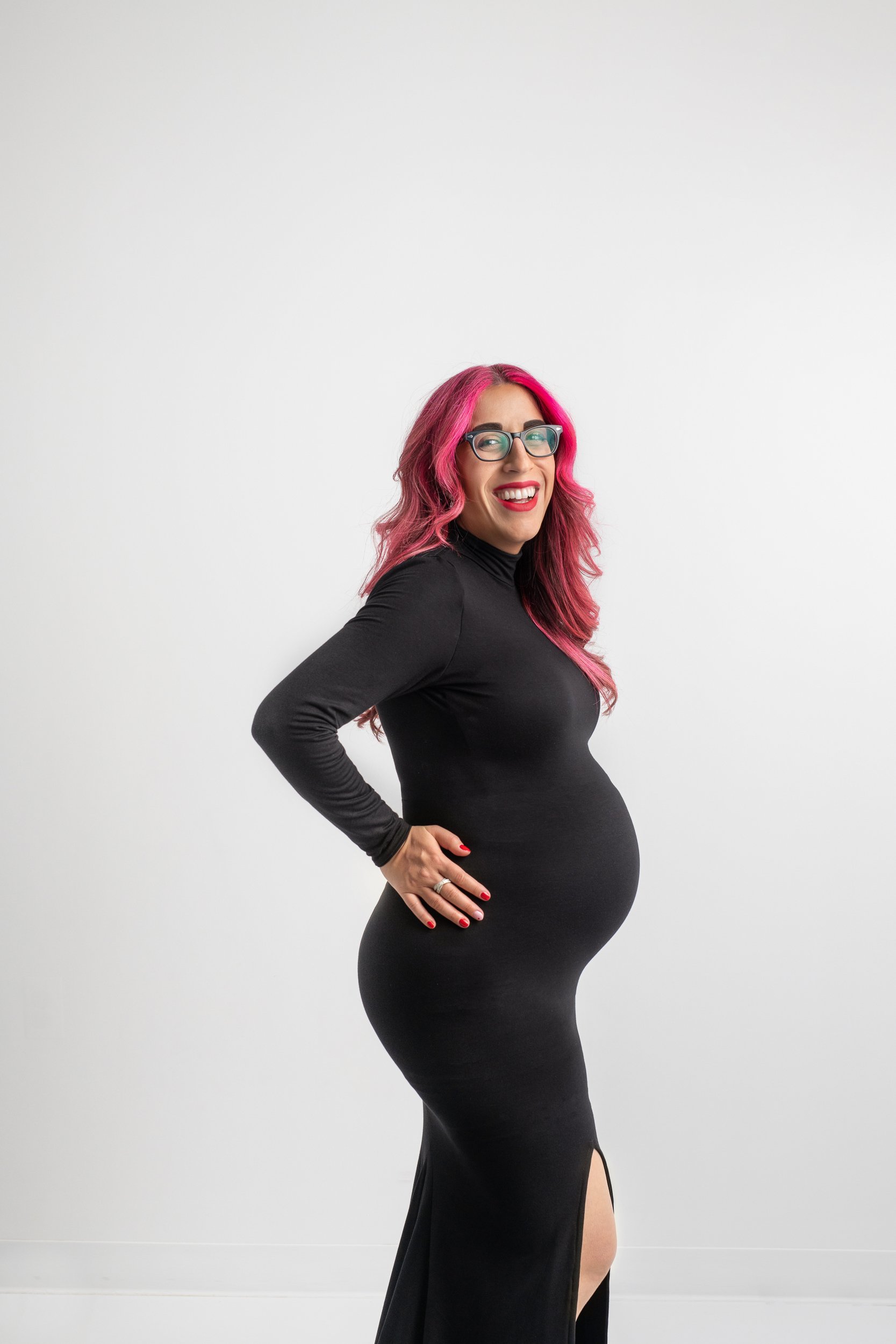  A stylish mom-to-be laughs while holding her baby bump in a New Jersey studio by Nicole Hawkin Photography. laughing mom NJ maternity #NicoleHawkinsPhotography #maternitysession #NJmaternityphotographer #NewJerseyphotographers #maternityphotos 