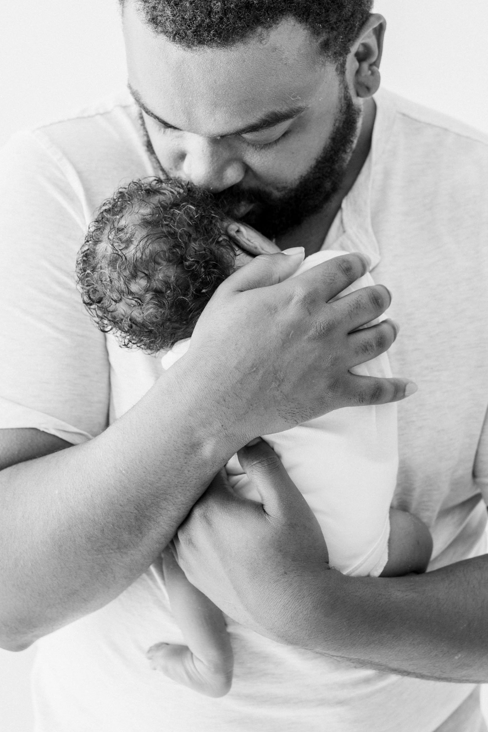  Father cuddles baby and kisses his head captured by Nicole Hawkins Photography from New Jersey. father kisses baby newborn portraits in NJ #nicolehawkinsphotography #NJbabyphotography #newbornportraits #NewJerseyStudioPhotography #newbornsession 