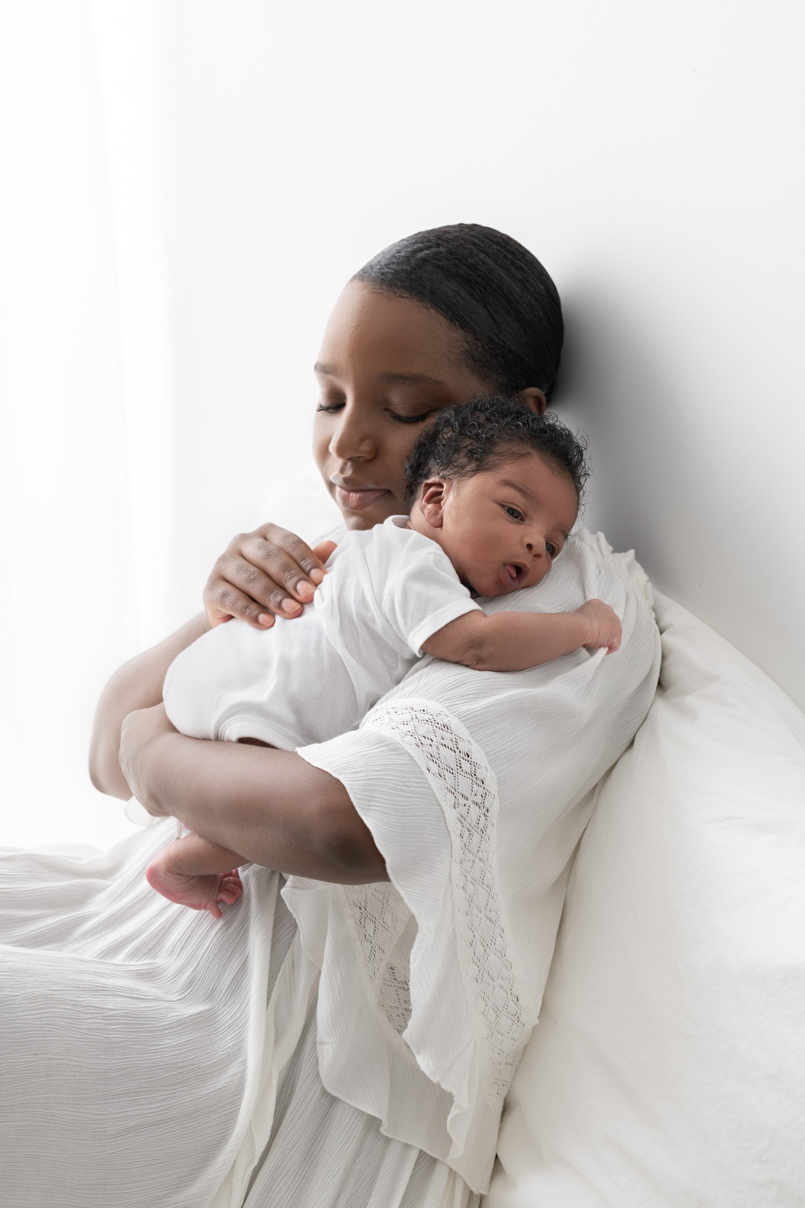  A newborn snuggles into his mother’s shoulder as she holds him by Nicole Hawkins Photography. mother-baby portrait motherhood portrait #nicolehawkinsphotography #NJbabyphotography #newbornportraits #NewJerseyStudioPhotography #newbornsession 