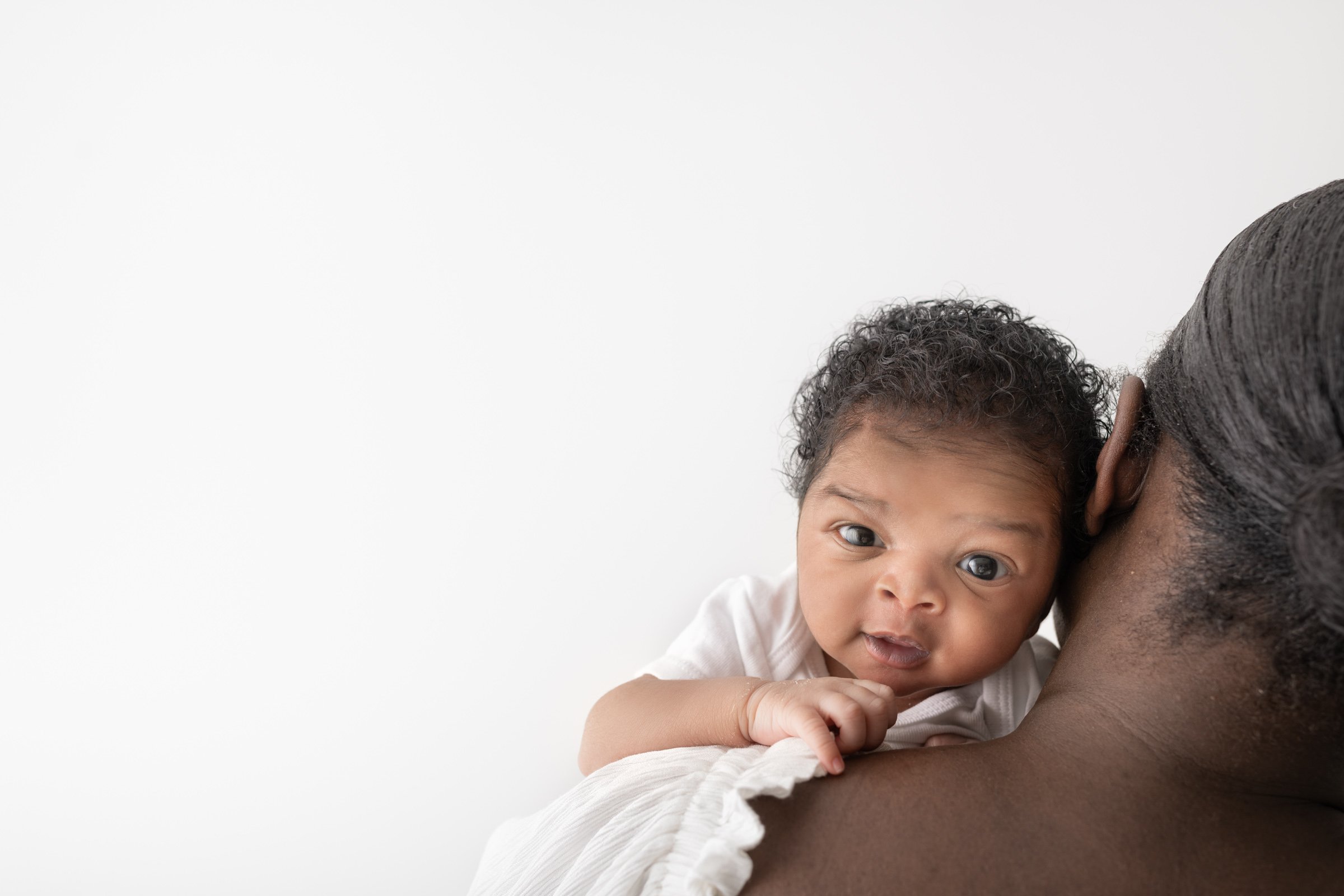  In New Jersey a newborn boy looks over his mother's shoulder captured by Nicole Hawkins Photography. over the shoulder baby portrait NJ studio #nicolehawkinsphotography #NJbabyphotography #newbornportraits #NewJerseyStudioPhotography #newbornsession