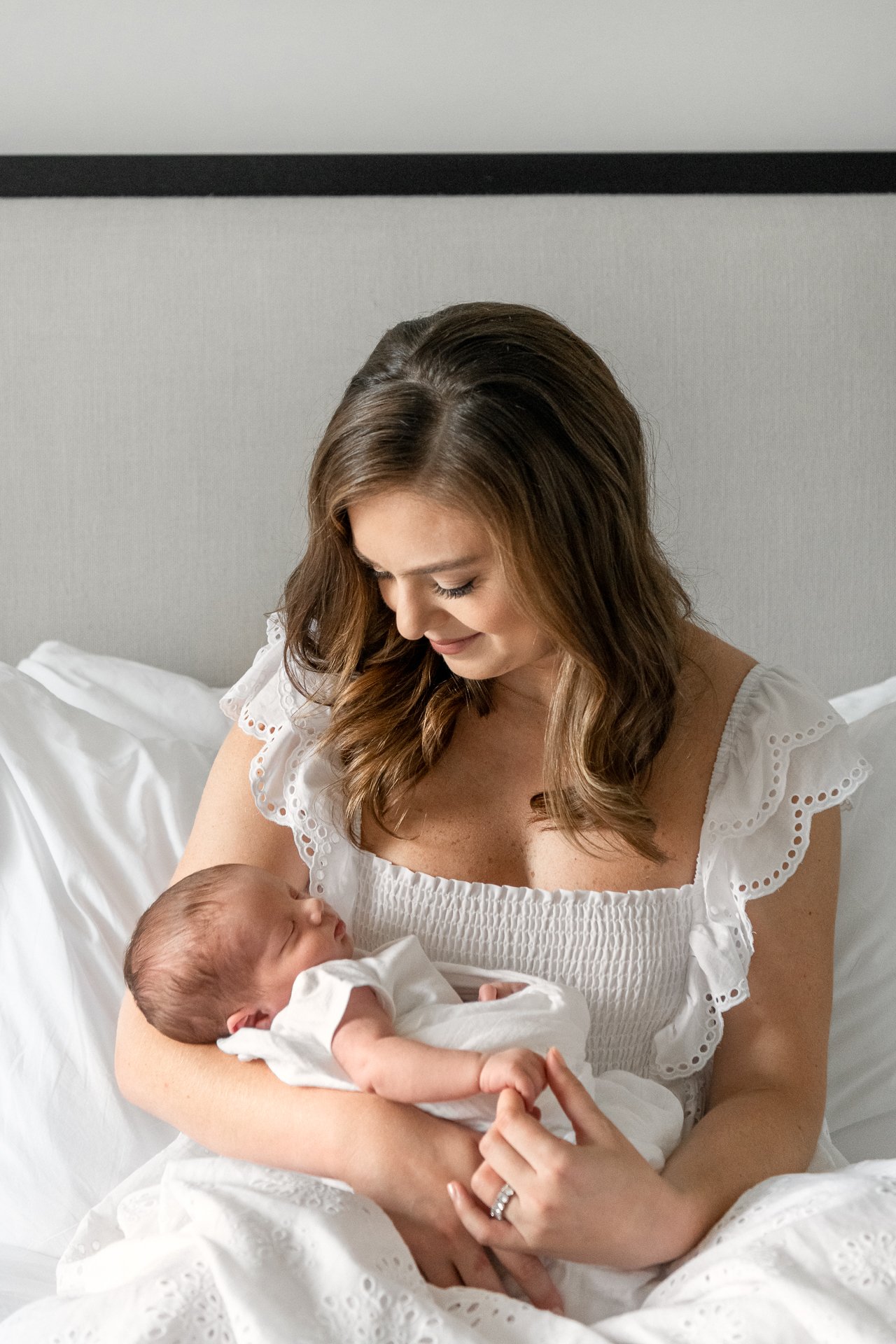  A mother in a white summer dress holds her new baby on a bed in NYC by Nicole Hawkins Photography. mother and baby portrait NYC baby photog #nicolehawkinsphotography #NYCbabyphotography #newbornportraits #NewYorkStudioPhotography #newbornsession 