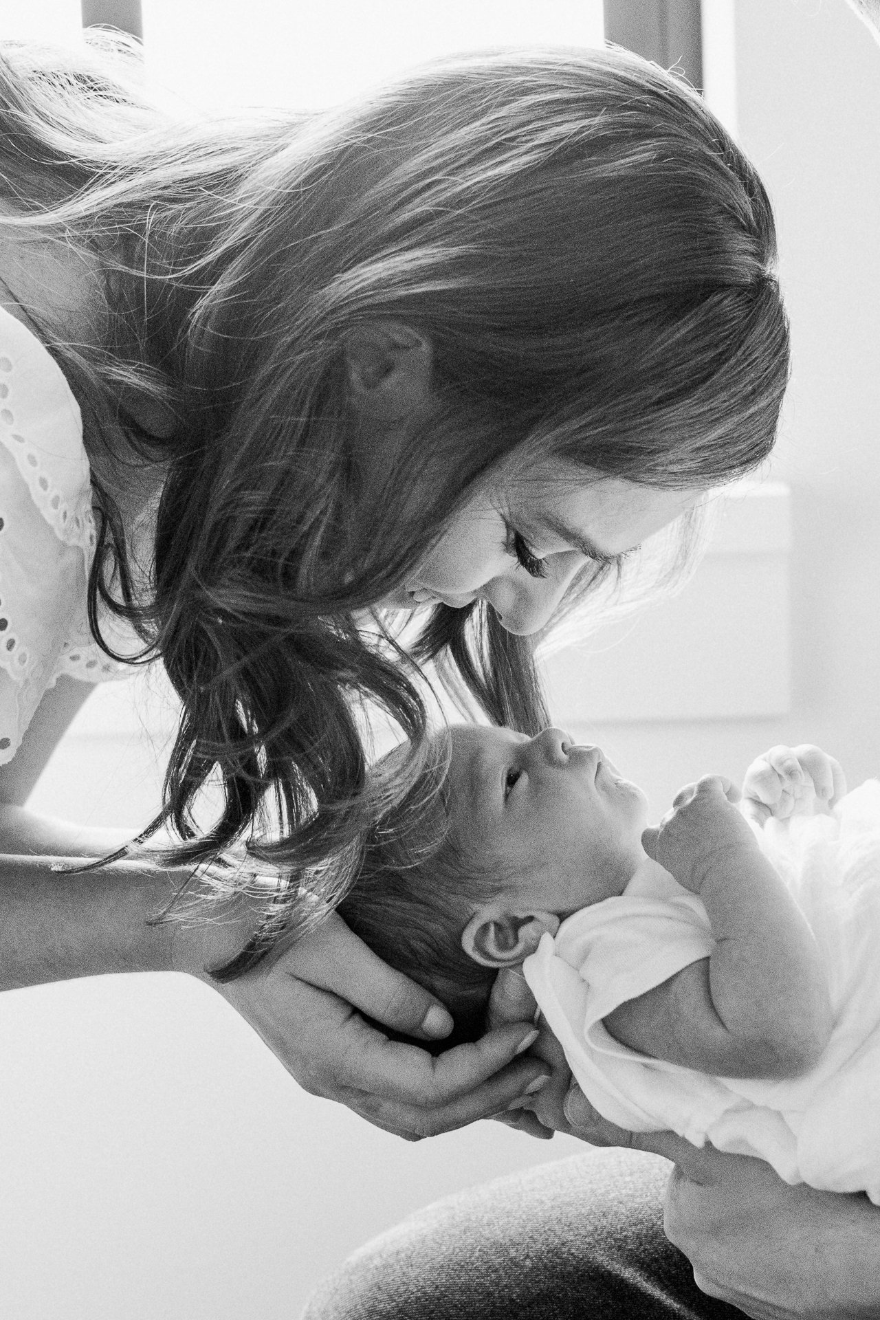  A black and white photo of a mother kissing the top of her baby's head by Nicole Hawkins Photography. black and white newborn photography #nicolehawkinsphotography #NYCbabyphotography #newbornportraits #NewYorkStudioPhotography #newbornsession 
