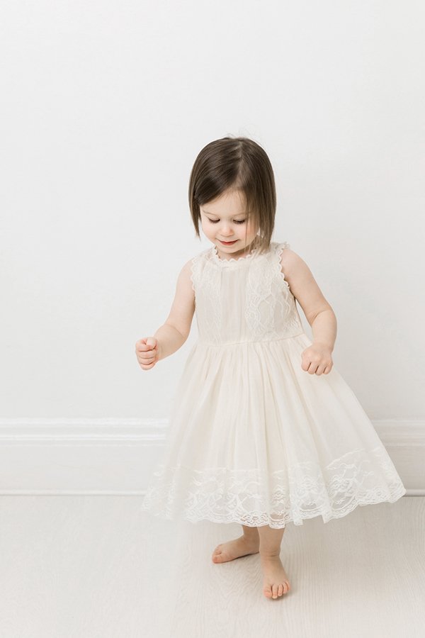 A little girl in a white lace dress at a studio in New Jersey by Nicole Hawkins Photography. white lace toddler dress white studio #nicolehawkinsphotography #NJstudionewborns #newbornsession #studionewborns #NJnewbornphotographers #NJphotographers 