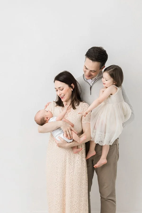  Nicole Hawkins Photography captures a mother holding a newborn as a father and sister look over her shoulder. family newborn portrait #nicolehawkinsphotography #NJstudionewborns #newbornsession #studionewborns #NJnewbornphotographers #NJphotographer