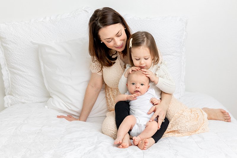  New Jersey photographer Nicole Hawkins Photography captures a mother and her two daughters on a white bed in NJ. mother with daughter #nicolehawkinsphotography #NJstudionewborns #newbornsession #studionewborns #NJnewbornphotographers #NJphotographer