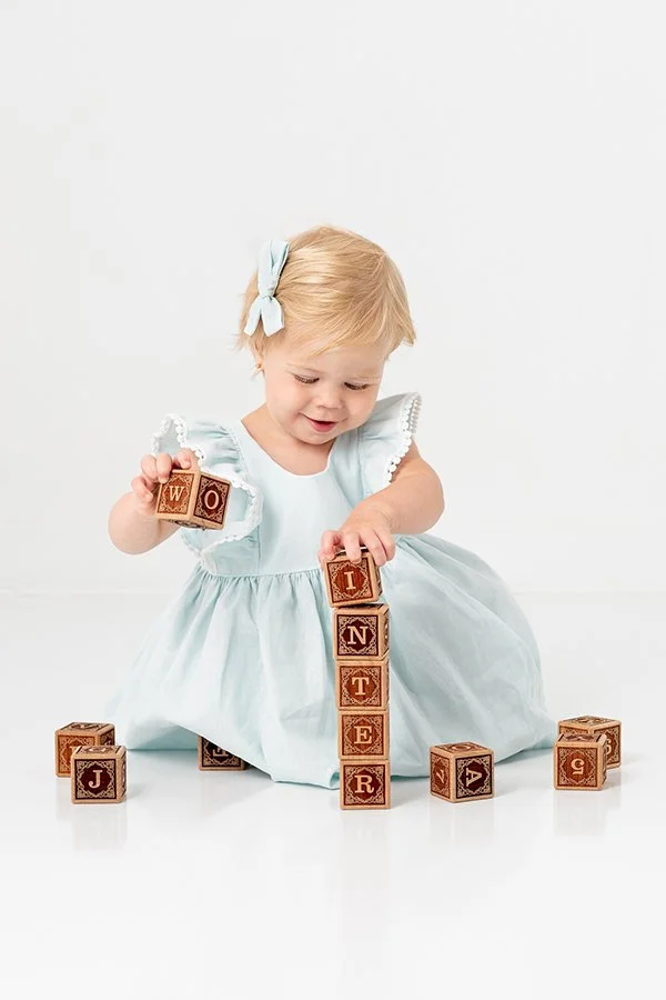  Toddler girl stacks blocks during a portrait session with New Jersey photographer Nicole Hawkins Photography. baby girl stacks blocks #nicolehawkinsphotography #NJstudioportraits #babyportraits #babygirlportraits #NJbabyphotographers #NJphotographer