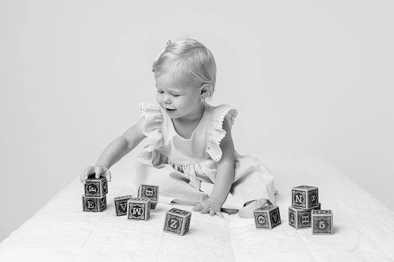  Nicole Hawkins Photography captures a toddler playing with wooden blocks during a baby portrait session. toddler wood photography blocks #nicolehawkinsphotography #NJstudioportraits #babyportraits #babygirl #NJbabyphotographers #NJphotographers 