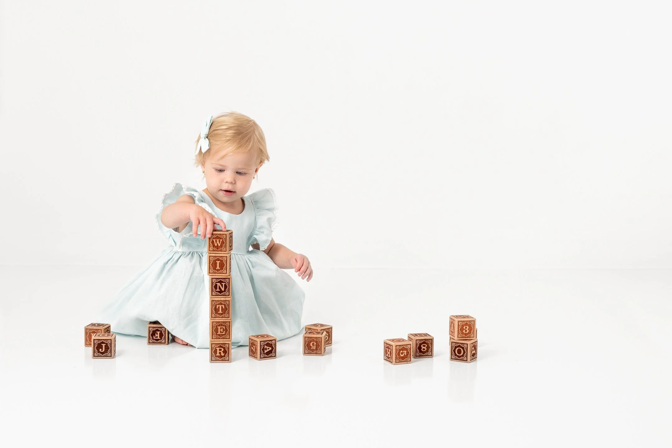  Little girl plays with wooden blocks at a studio in New Jersey by Nicole Hawkins Photography. toddler girl portraits #nicolehawkinsphotography #NJstudioportraits #babyportraits #babygirlportraits #NJbabyphotographers #NJphotographers 