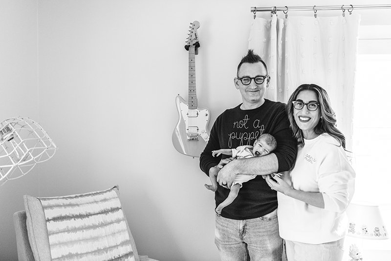  A black and white portrait of a husband and wife with their new baby by Nicole Hawkins Photography in NJ. spunky baby nursery decor #nicolehawkinsphotography #NJfamilyphotographer #inhomenewbornsession #nicolehawkinsnewborns #NJnewbornphotography 