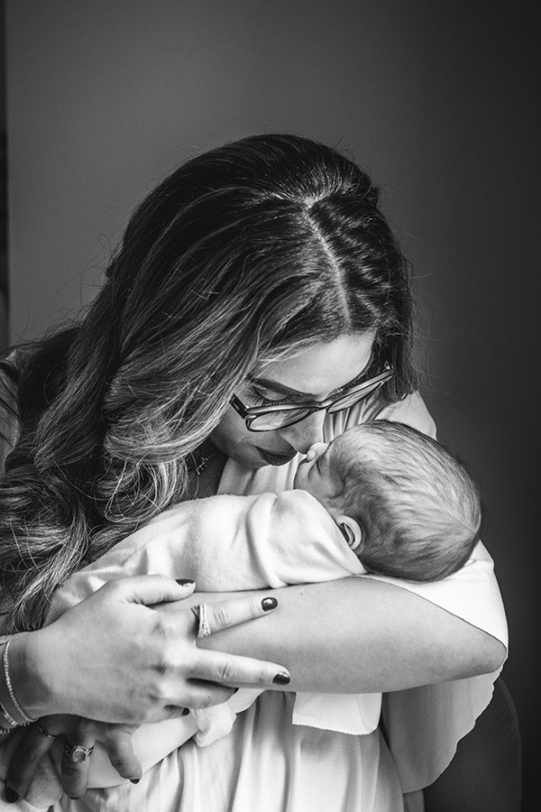  A black and white portrait of a mother kissing her baby girl by Nicole Hawkins Photography. mother kissing newborn baby in-home session #nicolehawkinsphotography #NJfamilyphotographer #inhomenewbornsession #nicolehawkinsnewborns #NJnewbornphotograph