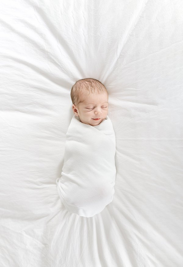  An all-white newborn portrait on a bed by Nicole Hawkins Photography in New Jersey. all white newborn photoshoot white swaddle #nicolehawkinsphotography #NJfamilyphotographer #inhomenewbornsession #nicolehawkinsnewborns #NJnewbornphotography 