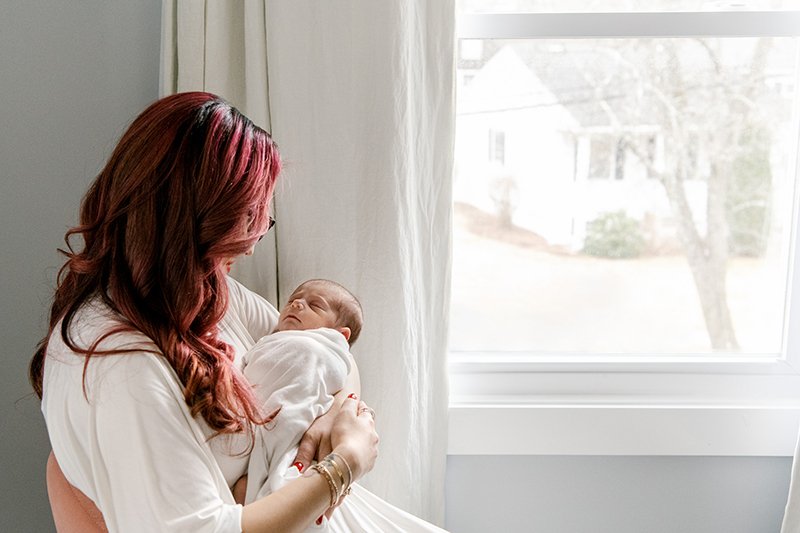  Next to a bright light window, a mother holds her baby girl by Nicole Hawkins Photography. bright window silhouette portraits. motherhood #nicolehawkinsphotography #NJfamilyphotographer #inhomenewborn #nicolehawkinsnewborns #NJnewbornphotography 