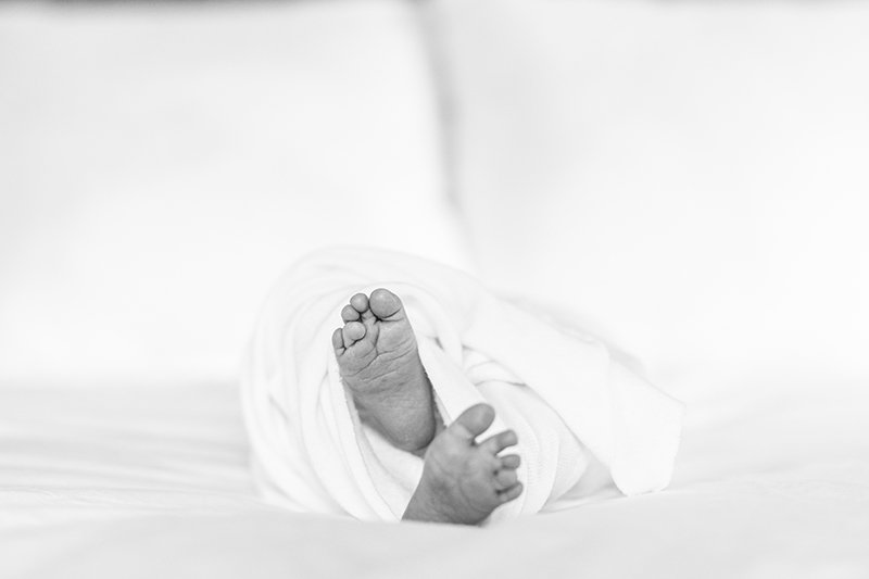  Nicole Hawkins Photography captures a zoomed-up portrait of baby toes poking out of a swaddle. baby feet New Jersey family photographer #nicolehawkinsphotography #NJfamilyphotographer #inhomenewbornsession #nicolehawkinsnewborns #NJnewbornphotograph