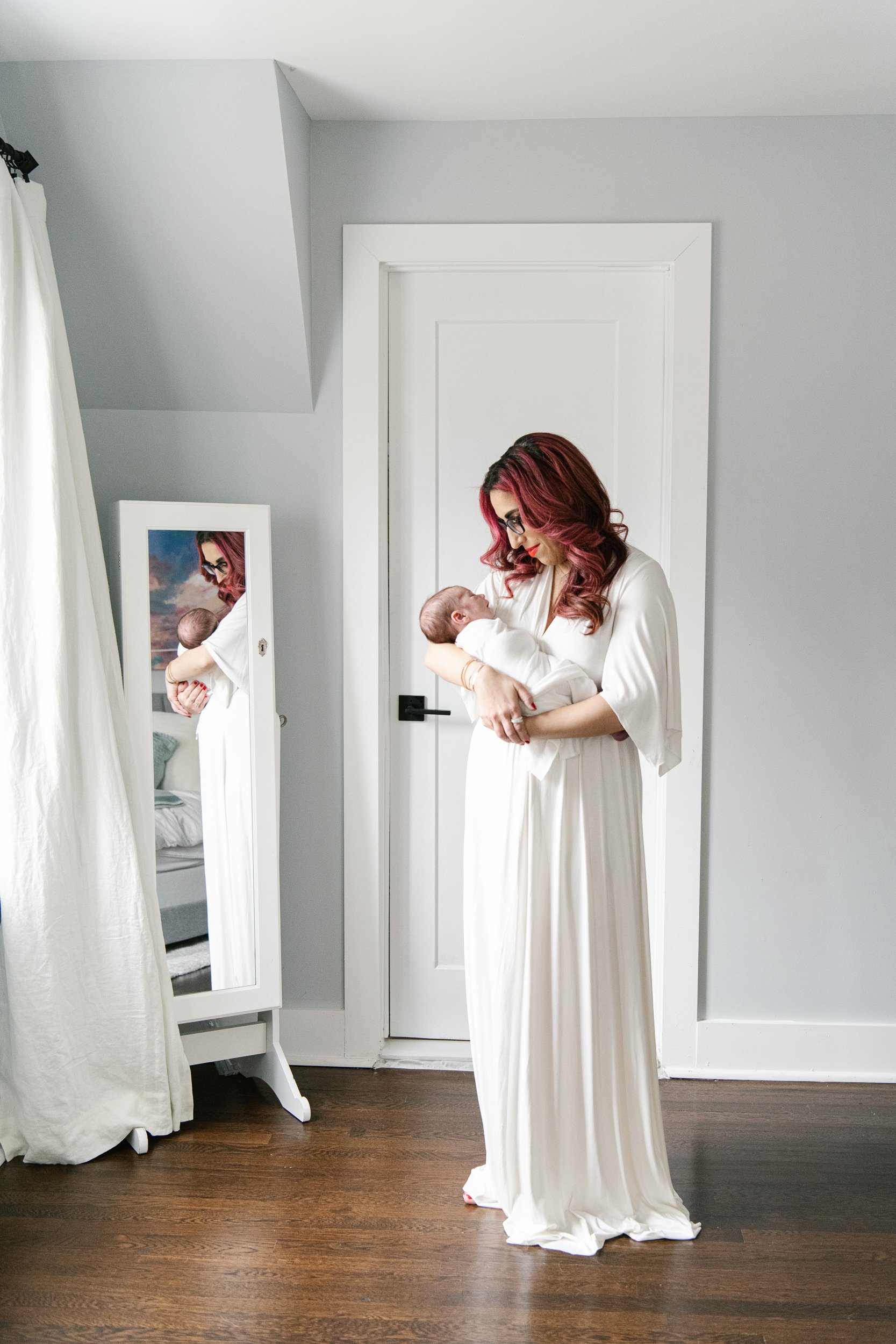 New Jersey newborn photographer Nicole Hawkins Photography captures a mother holding a baby in the mirror. mirror motherhood shots #nicolehawkinsphotography #NJfamilyphotographer #inhomenewbornsession #nicolehawkinsnewborns #NJnewbornphotography 