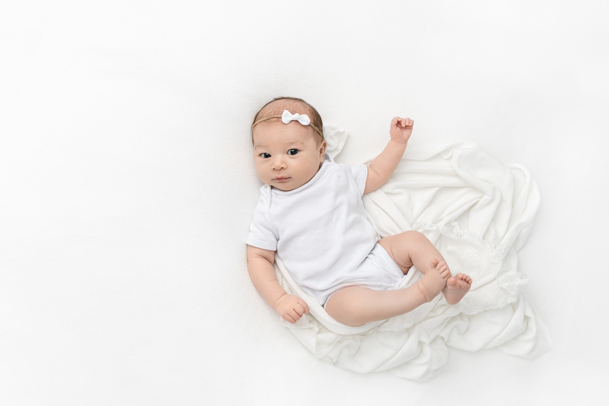 Baby girl in a white onesie at a studio captured by Nicole Hawkins PHotography a newborn photographer. Maplewood photographers baby girl #NicoleHawkinsPhotography #studionewbornportraits #NJstudiophotographer #NJnewborns #NicoleHawkinsNewborns 