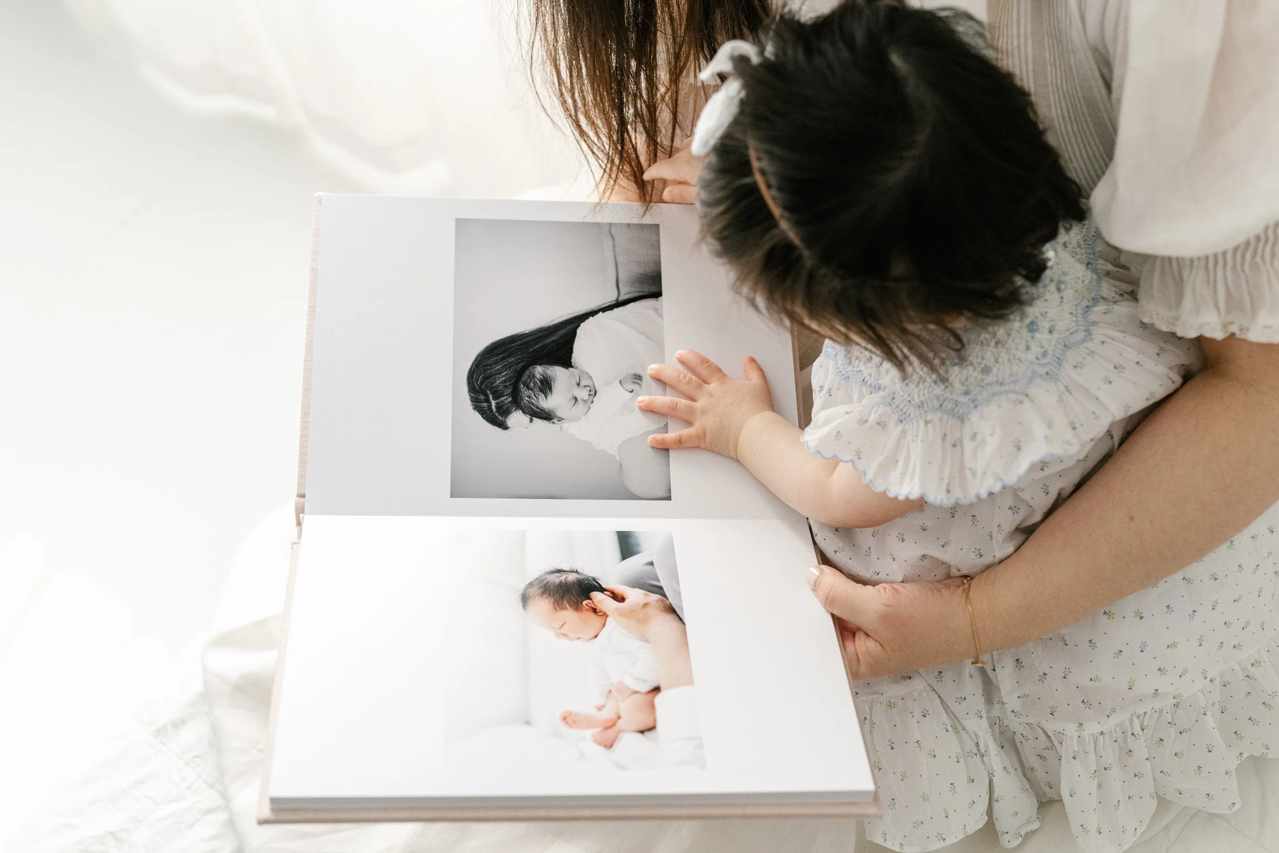  Close up of a one-year-old girl looking at newborn pictures by Nicole Hawkins Photography in an NJ studio. first birthday portraits baby book #nicolehawkinsphotography #nicolehawkinsbirthday #nicolehawkinsportraits #NJstudiophotography #1stbirthday 