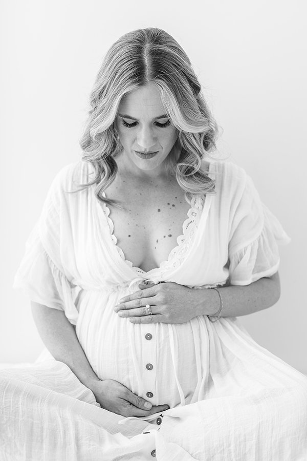  New Jersey Maternity Photographer Nicole Hawkins Photography captures a straight-on portrait of a mother sitting in a studio. deep v maternity gown #nicolehawkinsphotography #nicolehawkinsmaternity #maternityportraits #NJstudiophotography #mommatobe