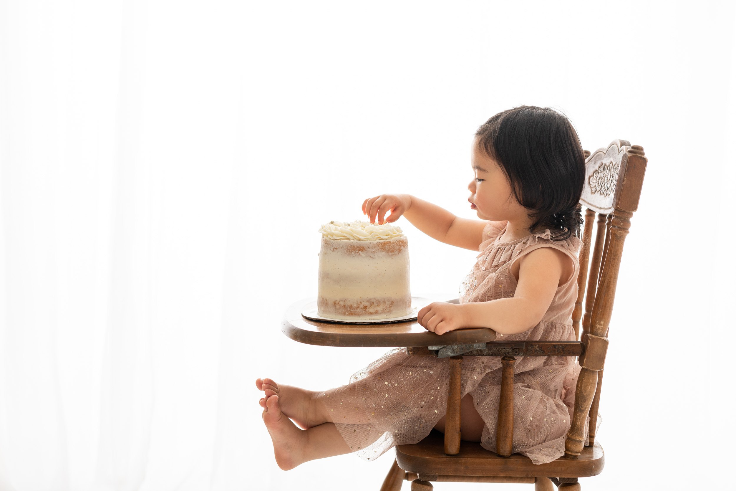 Portrait of two year old in vintage highchair with beautiful birthday cake