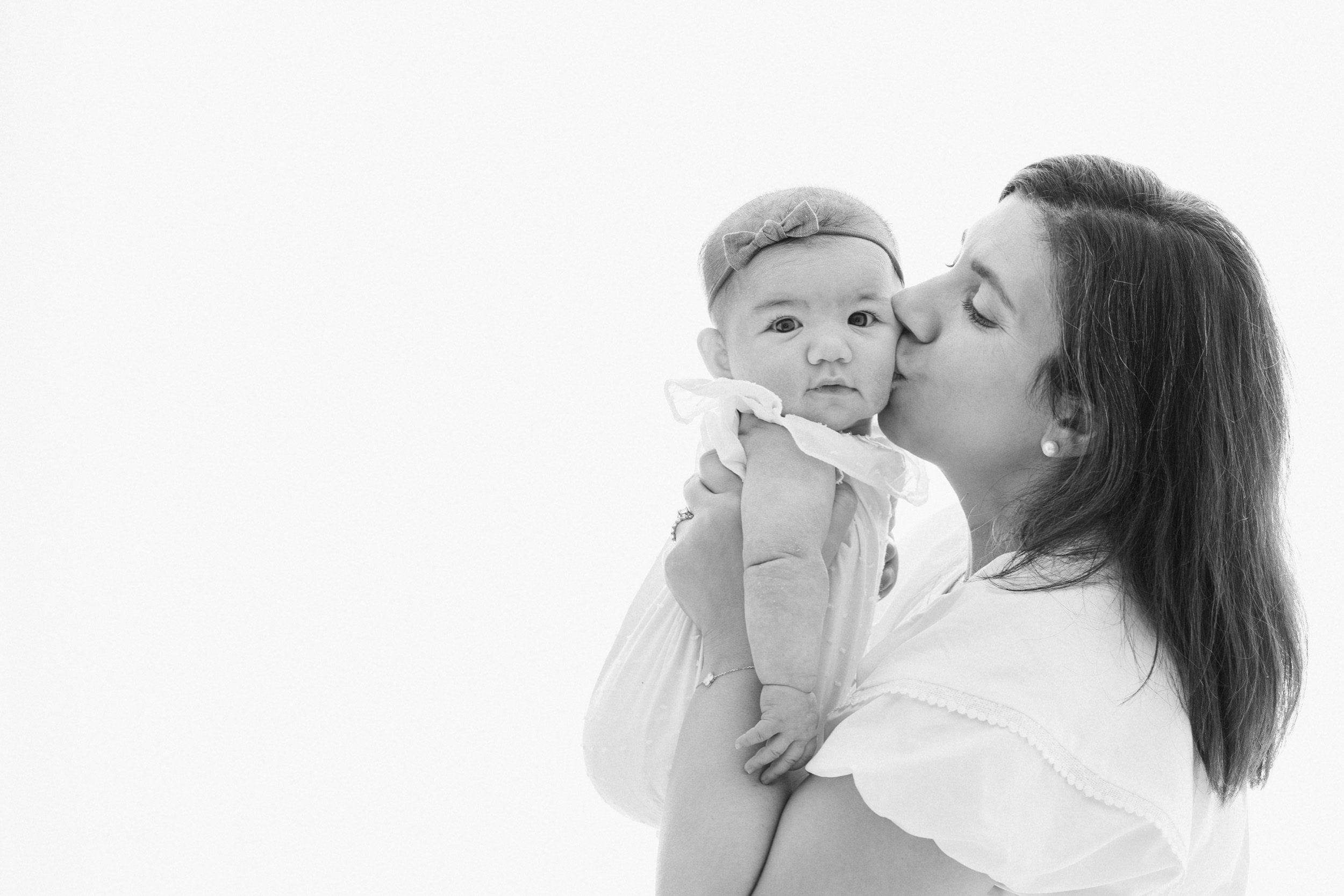 Black and white portrait of mother kissing her sweet 3 month old baby