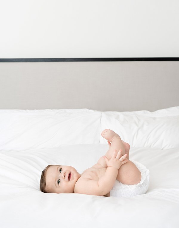  During an at-home session in New Jersey, Nicole Hawkins Photography captures a baby playing on a bed. chunky baby boy #NicoleHawkinsPhotography #NicoleHawkinsMilestones #BabyMilestoneSession #NJfamilyphotographer #Inhomephotography #babyportraits 