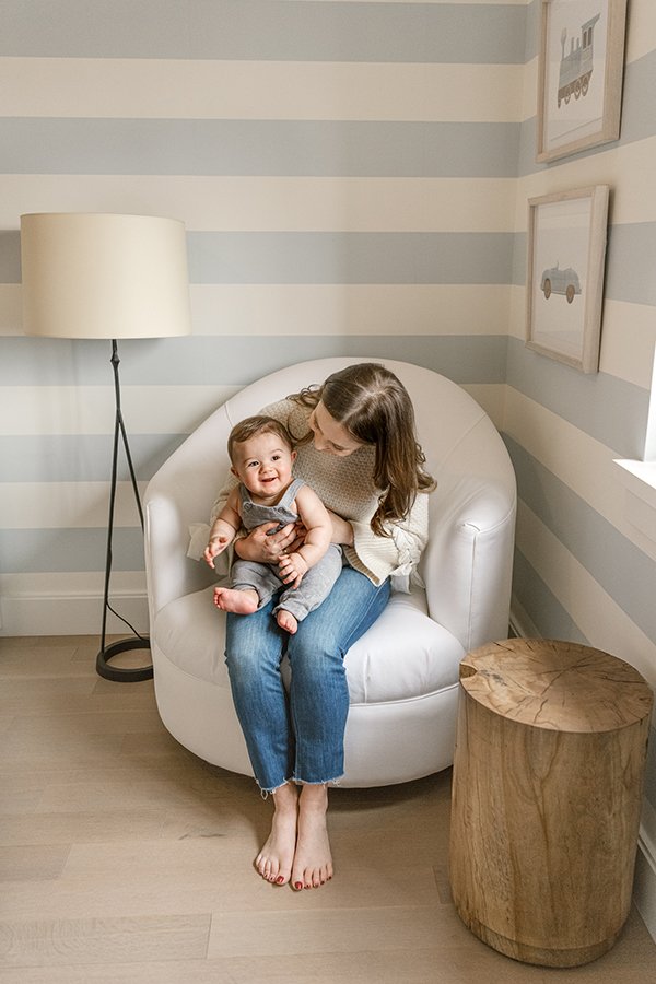 Sitting in a chair in a nursery a mother and baby interact captured by Nicole Hawkins Photography. motherhood portraits #NicoleHawkinsPhotography #NicoleHawkinsMilestones #BabyMilestoneSession #NJfamilyphotographer #Inhomephotography #babyportraits 