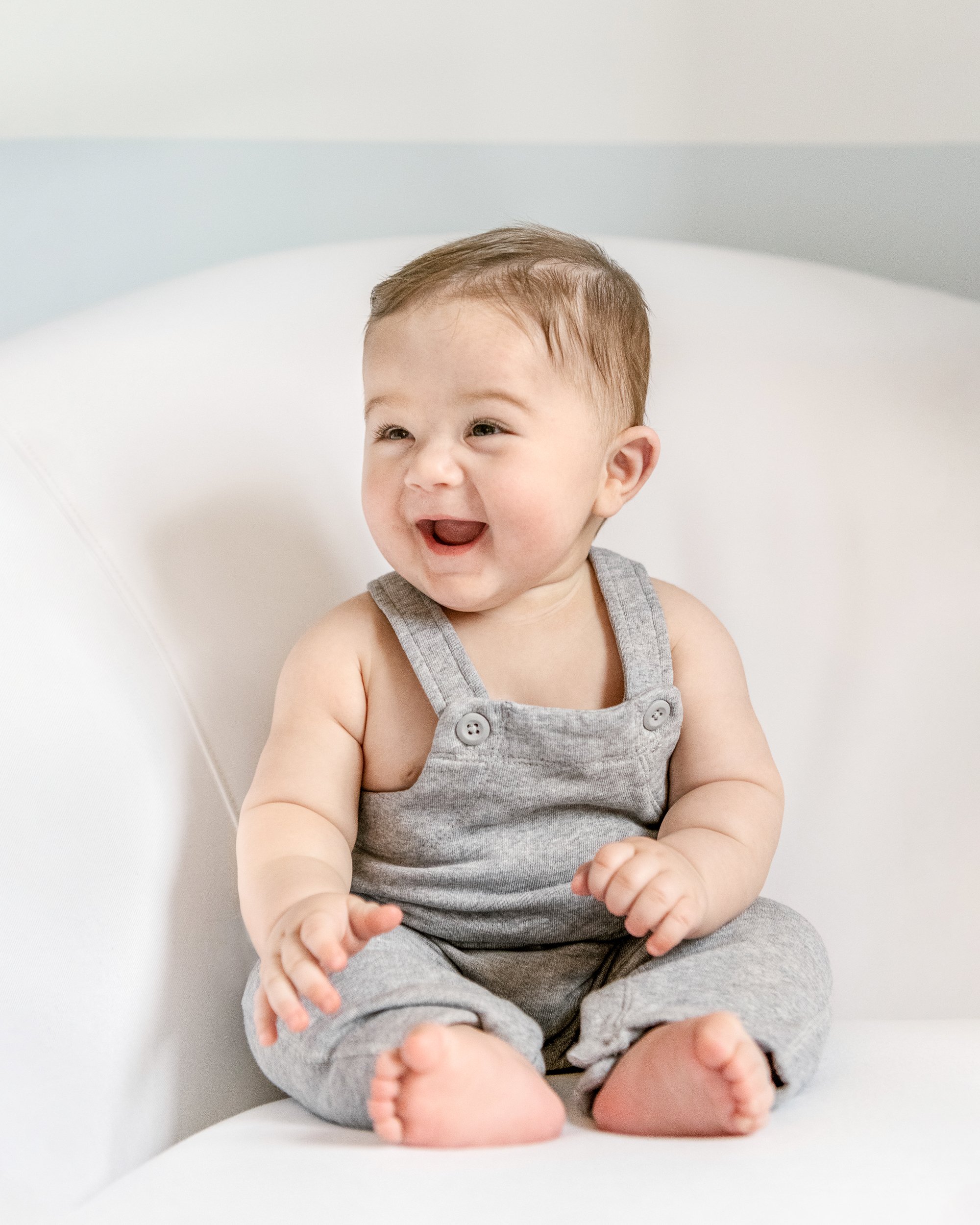  Nicole Hawkins Photography captures a smiley little boy in gray overalls during a 6-month milestone session. NJ photog #NicoleHawkinsPhotography #NicoleHawkinsMilestones #BabyMilestoneSession #NJfamilyphotographer #Inhomephotography #babyportraits 