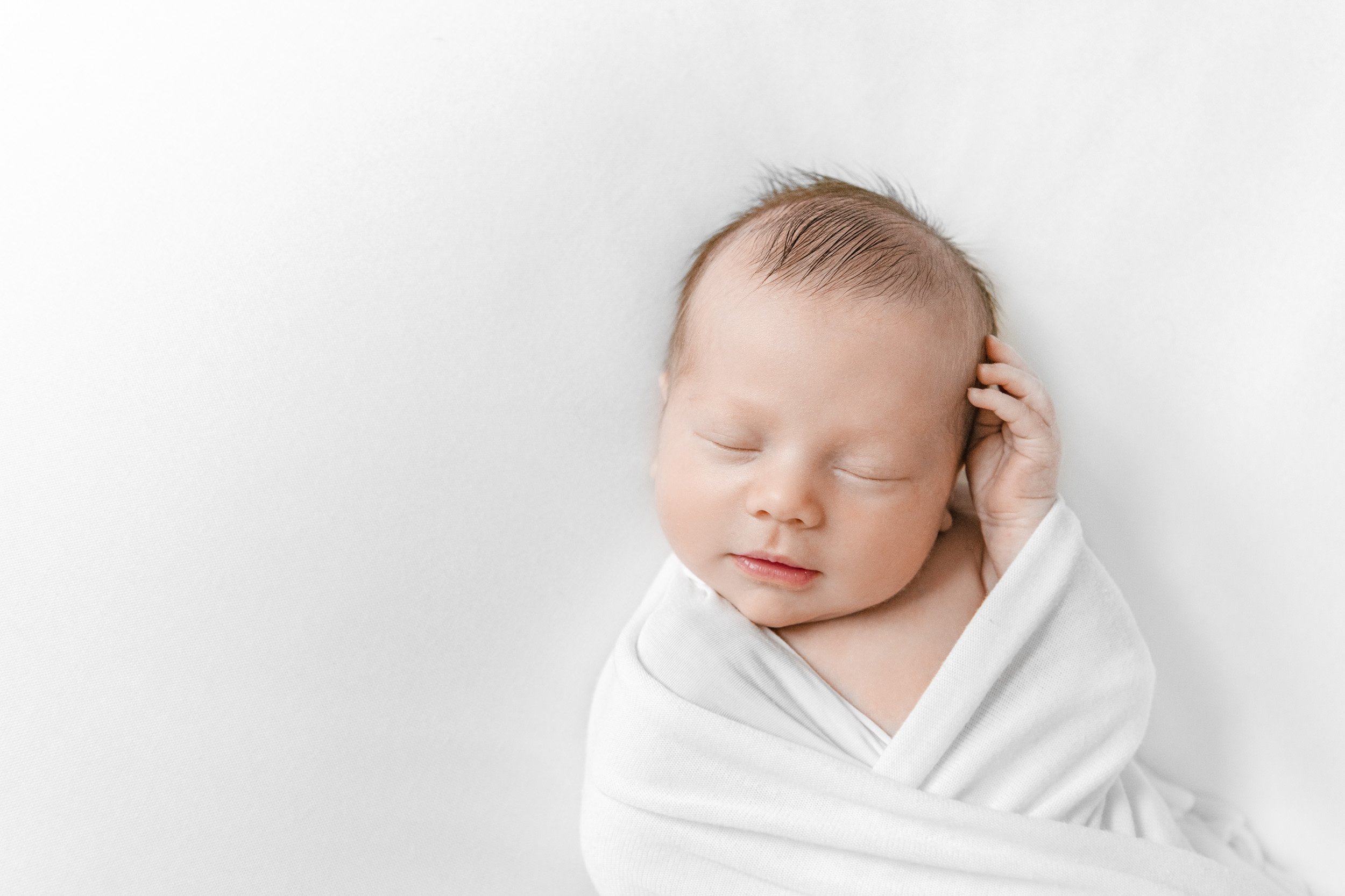  Newborn baby swaddled in a white blanket in a New Jersey home by Nicole Hawkins Photography. sleeping baby boy white swaddle #NewbornSession #NJfamilyphotographer #Inhomebabyphotography #newborn #NicoleHawkinsPhotography #NicoleHawkinsNewborns 