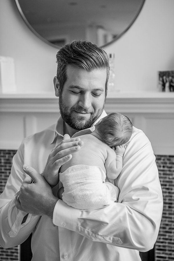  Father holds his newborn baby with Nicole Hawkins Photography during a newborn session in NJ. father smiling at son father portrait #NewbornSession #NJfamilyphotographer #Inhomebabyphotography #newborn #NicoleHawkinsPhotography #NicoleHawkinsNewborn