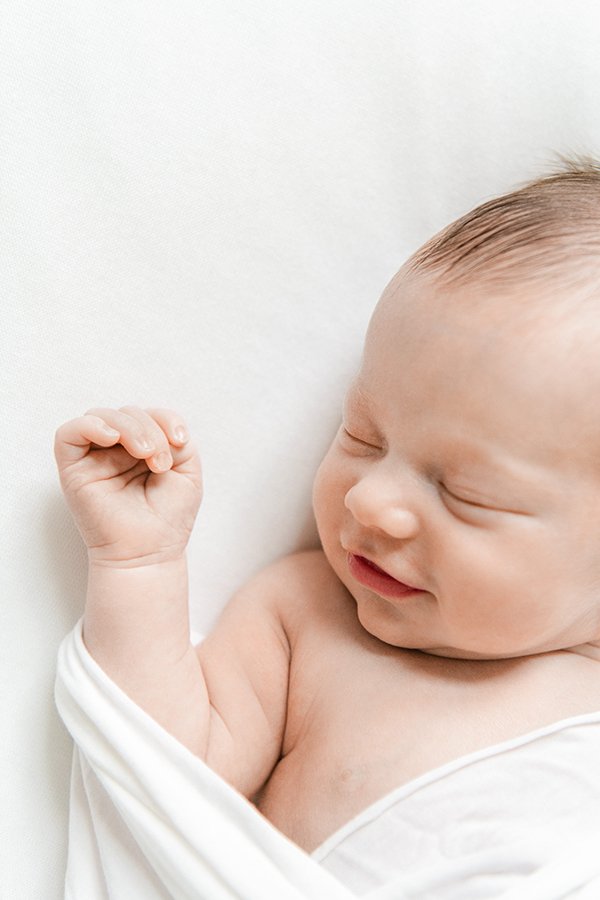  A detailed up-close portrait of a smiling sleeping newborn by Nicole Hawkins Photography. detailed sleeping baby all-white portrait #NewbornSession #NJfamilyphotographer #Inhomebabyphotography #newborn #NicoleHawkinsPhotography #NicoleHawkinsNewborn