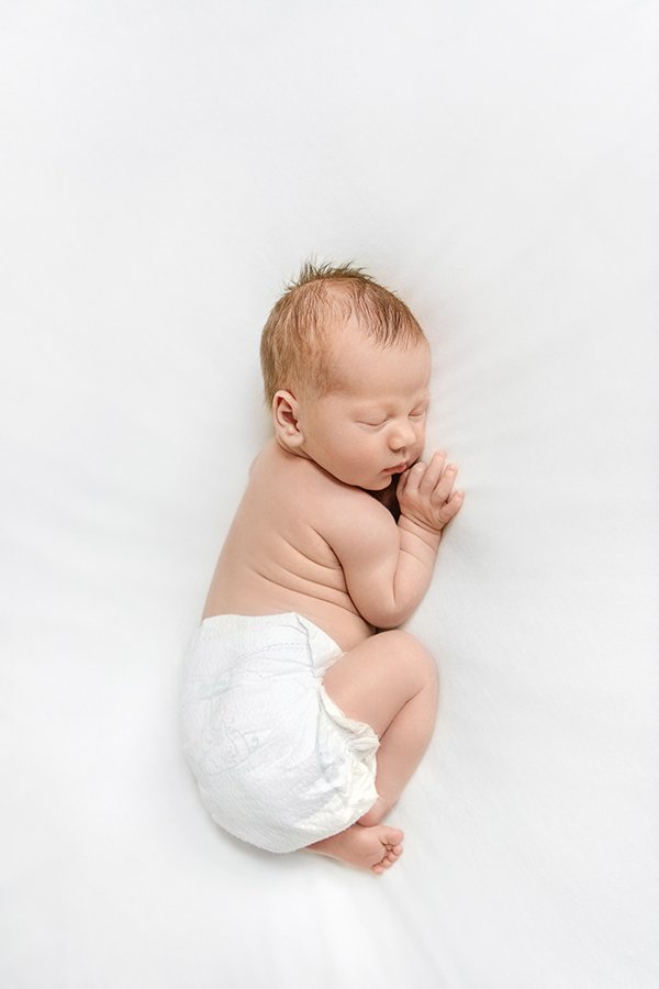  Curled up newborn on a white sheet during an at-home session by Nicole Hawkins Photography. at home newborn NJ photographer #NewbornSession #NJfamilyphotographer #Inhomebabyphotography #newborn #NicoleHawkinsPhotography #NicoleHawkinsNewborns 