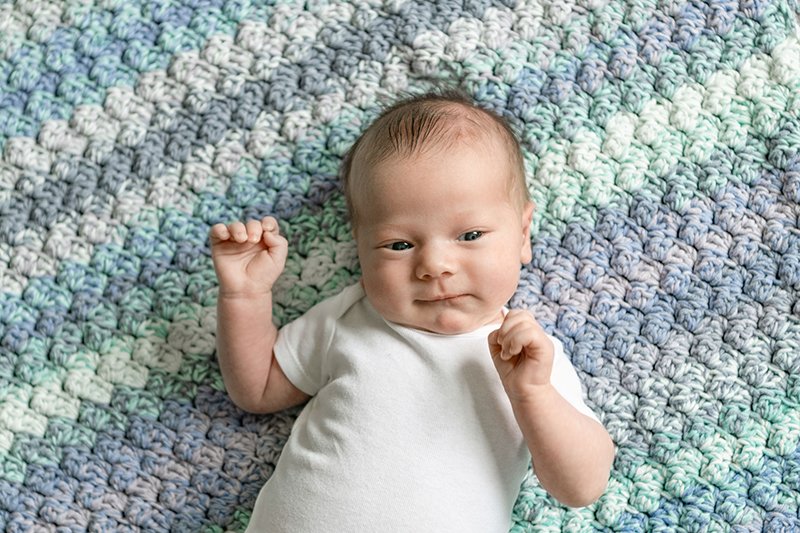  With eyes wide open a newborn lays on a blue blanket by Nicole Hawkins Photography in New Jersey. eyes open baby portrait #NewbornSession #NJfamilyphotographer #Inhomebabyphotography #newborn #NicoleHawkinsPhotography #NicoleHawkinsNewborns 