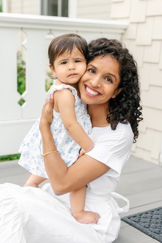 Mom in a white dress with beautiful dark curly hair snuggles her baby girl on their home’s front steps. #newjersyphotographers #njfamilyphotoographer #nicolehawkinsphotography #nicolehawkinsfamilies #inhomeportraits #glenridge #newjersey #babygirl 