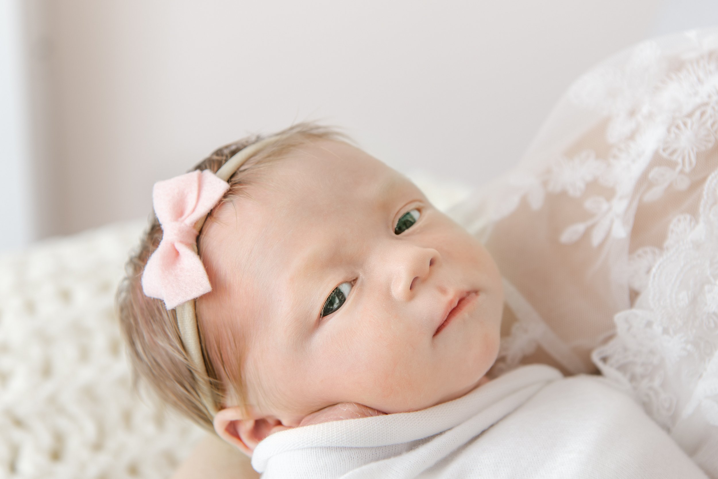  Beautiful newborn baby girl in a white swaddle wearing a pink bow rocking with mom in a white lace dress. #newbornsession #njfamiyphotographer #inhomephotography #nicolehawkinsnewborns #nicolehawkinsphotography #secondchild #chatham #newjersey 