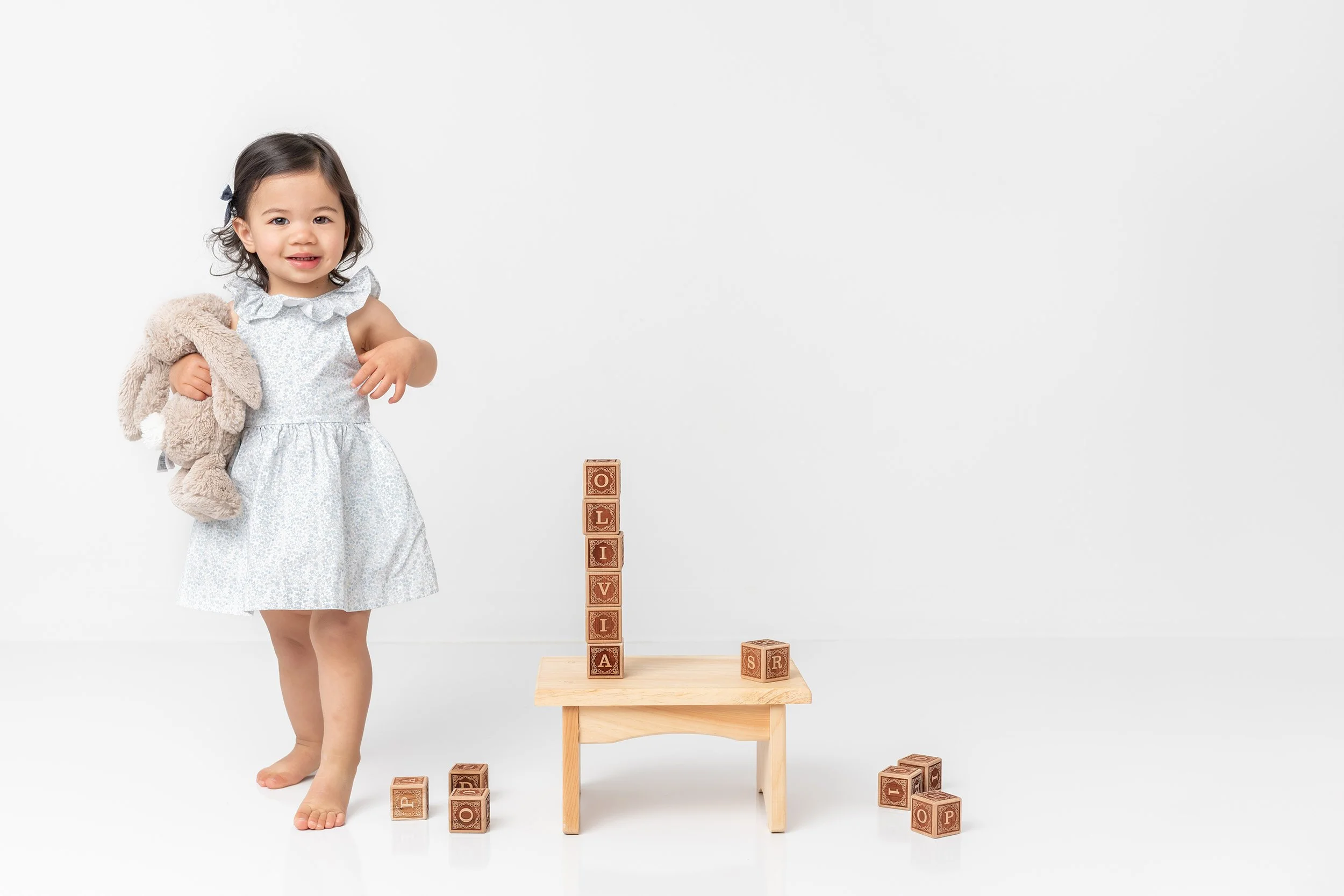  Two year old Asian toddler holding stuffed bunny in white portrait studio 