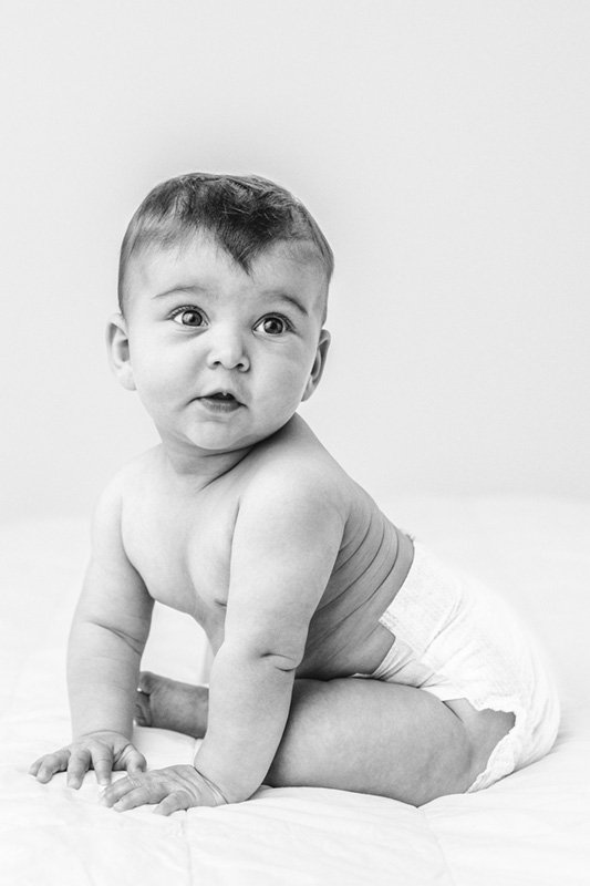  Black and white portrait of a naked baby in a diaper in a studio by Nicole Hawkins Photography. black and white portrait of baby #sixmonthbabyportraits #NJPhotographer #NicoleHawkinsPhotography #NicoleHawkinsBabies #BabyStudioPhotography    